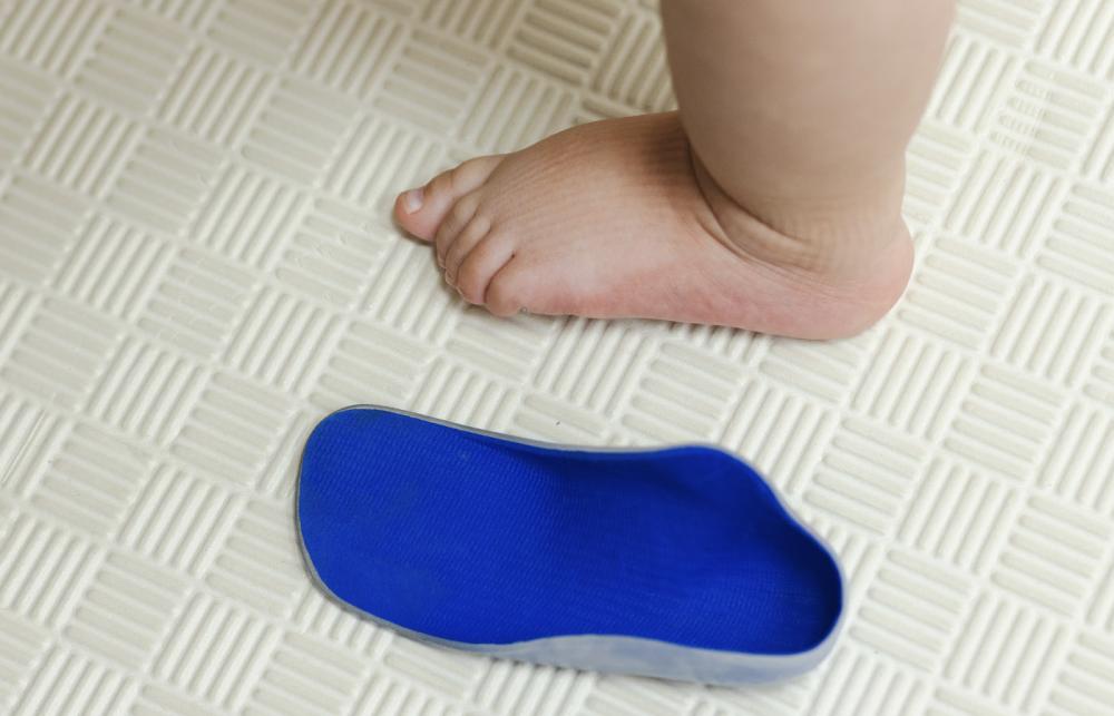 Child standing beside orthotic insoles for paediatric foot support