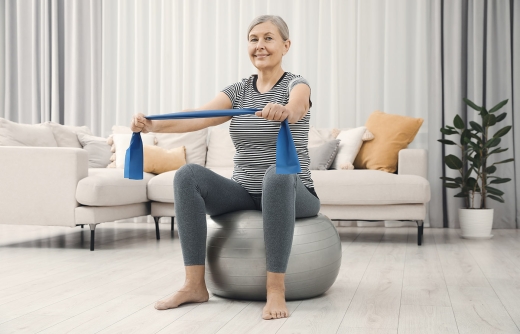 Older lady on exercise ball with resistance band