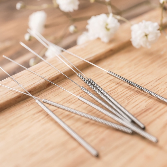 Sterile acupuncture needles arranged on a wooden surface for clinical use