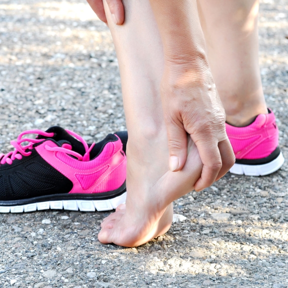 Person holding a painful heel to illustrate heel spur and plantar fascia discomfort