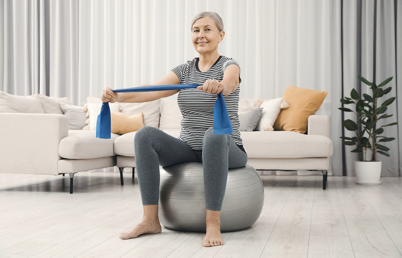 Older lady on exercise ball with resistance band